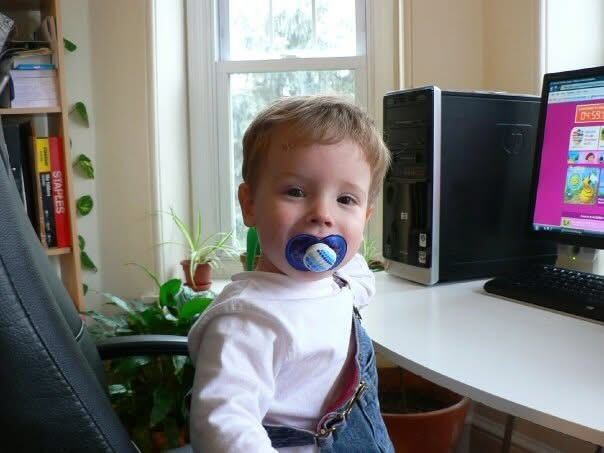 little baby me sitting in front of a computer smiling